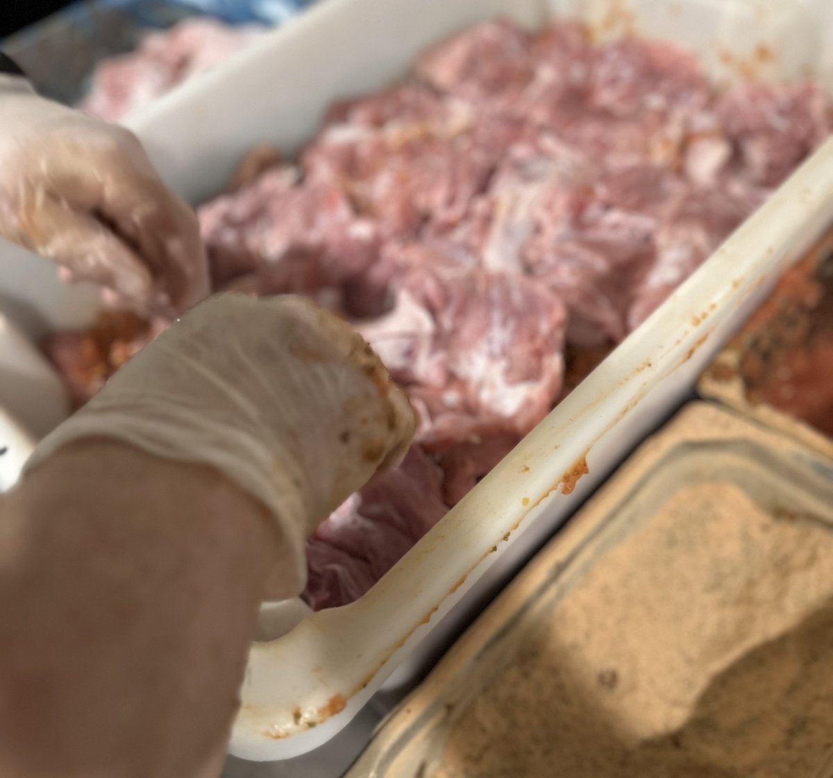 Yassas kitchen chef hand-rubbing housemade herb marinade into chicken maryland for charcoal gyros - Melbourne Greek restaurant